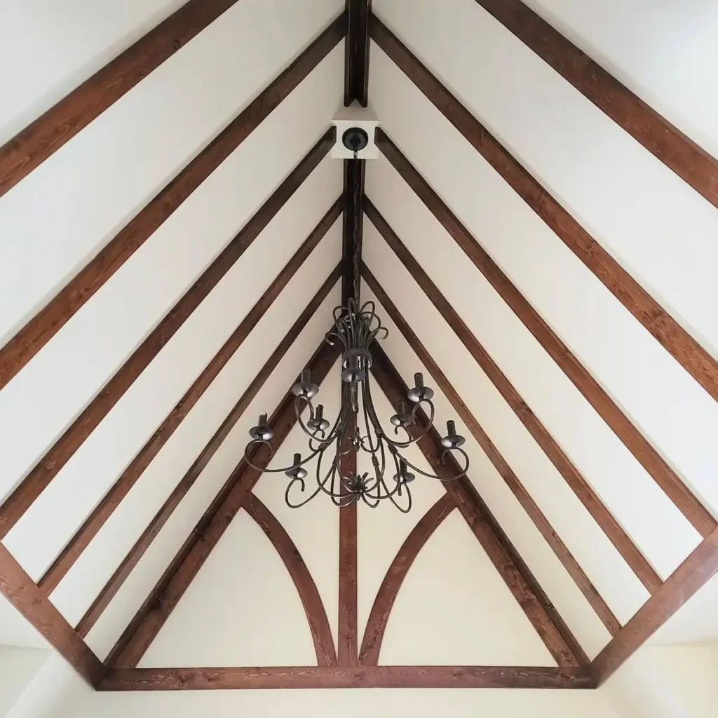 Modern Tudor Interior Design: A Definitive Guide 23 A vaulted ceiling in a Tudor style house interior, showing the graphic contrast between dark wood beams and crisp white paint.