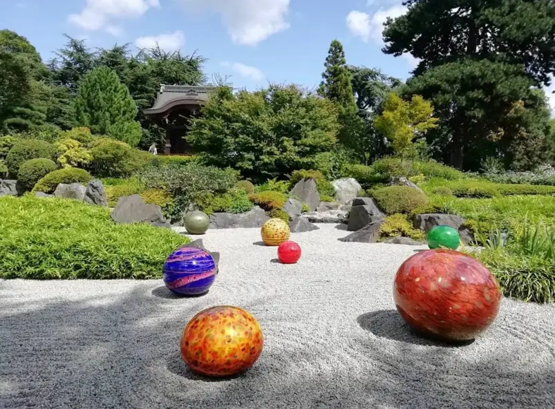 Raked gravel zen garden featuring a contemporary art installation of colorful glass spheres.