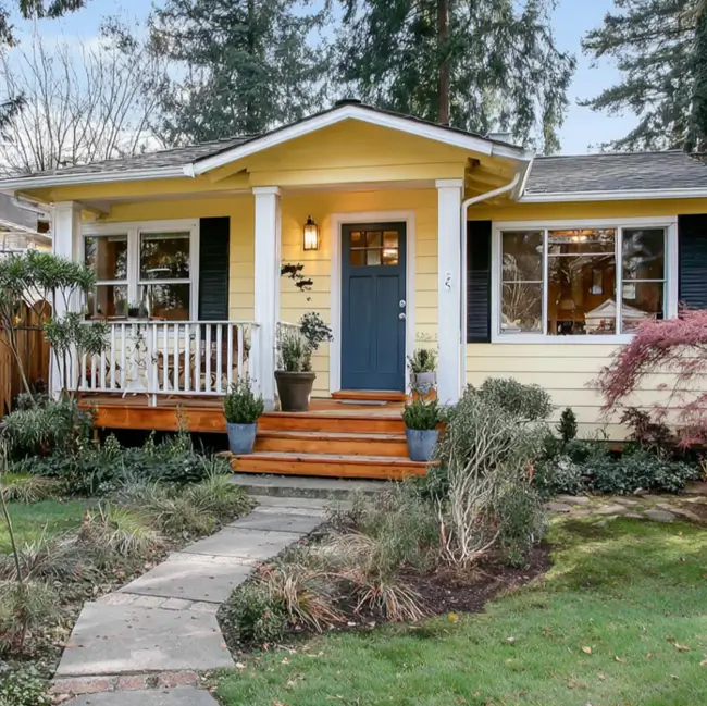 A classic ranch home with cheerful yellow siding, a dark blue door, and a front porch.