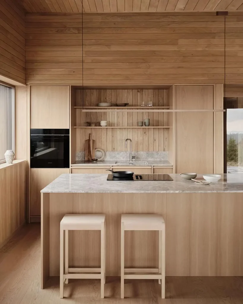 A Japanese inspired kitchen with cohesive light wood paneling on walls and ceiling, and a grey marble island.