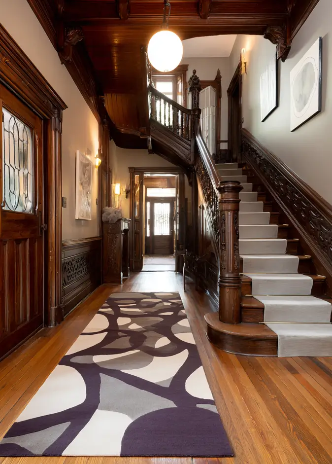 Modern Tudor Interior Design: A Definitive Guide 25 A grand, dark wood Tudor staircase with a modern, light-colored stair runner and a contemporary graphic rug.
