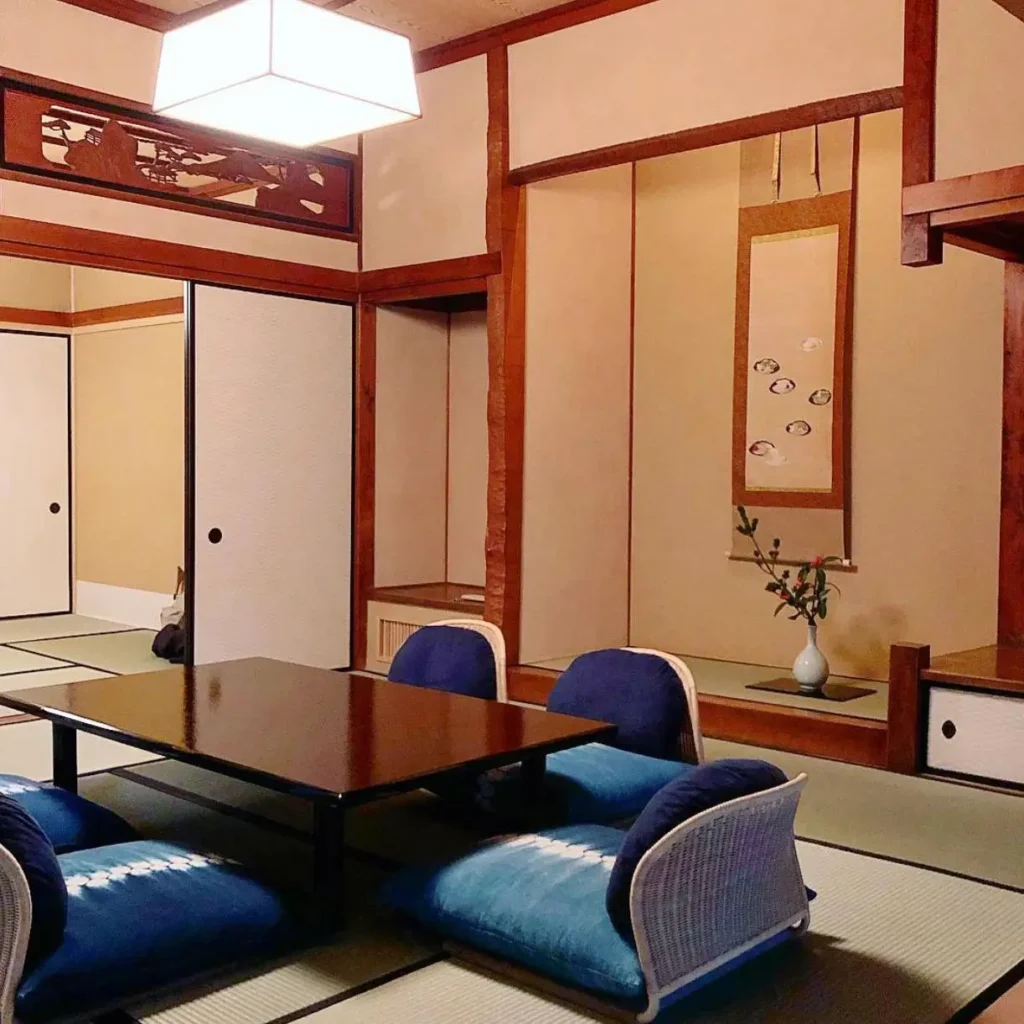 Traditional Japanese tatami room with a tokonoma alcove, hanging scroll, and carved wooden ranma.