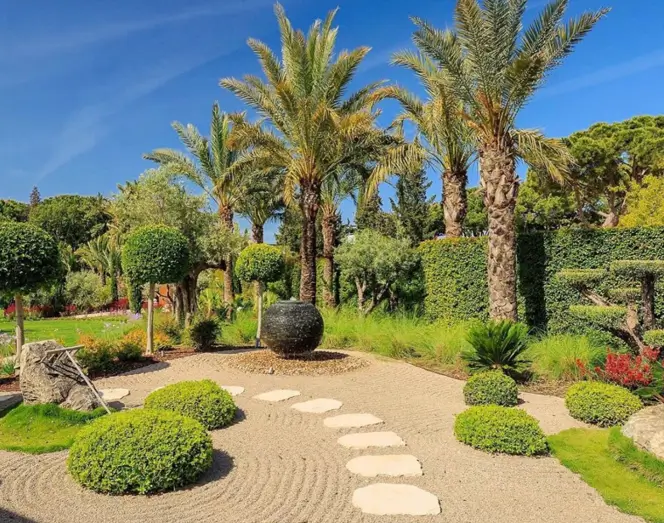Zen garden fusion design with a raked sand path, stepping stones, and palm trees.