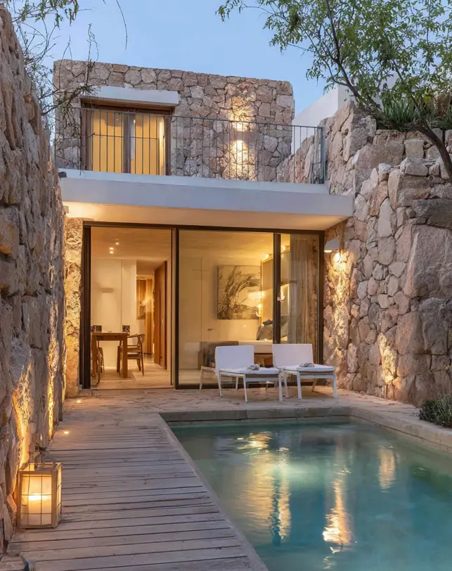 38 Small Mediterranean-Style Homes That Define Coastal Charm 27 Small Mediterranean-style home courtyard oasis featuring high stone walls, large glass doors, and a narrow lap pool.