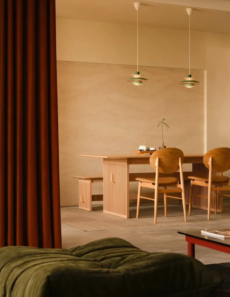 A Japandi-style dining room with a slatted wood table, minimalist chairs, and a textured plaster wall.