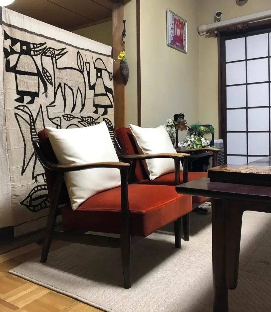 A traditional Japanese style living room in a home, featuring velvet chairs and a shoji screen.