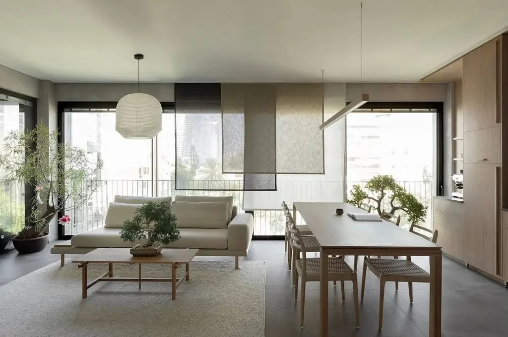 Modern open-plan living room featuring bonsai trees as Japanese living room decor and a paper lantern.