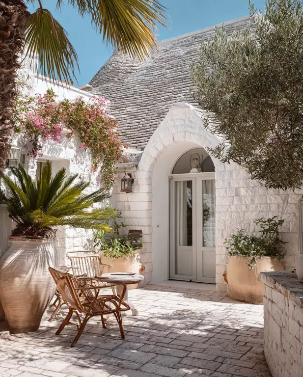 38 Small Mediterranean-Style Homes That Define Coastal Charm 32 Small Mediterranean house design with Trullo-inspired white stone walls, a conical roof, and a rustic patio.