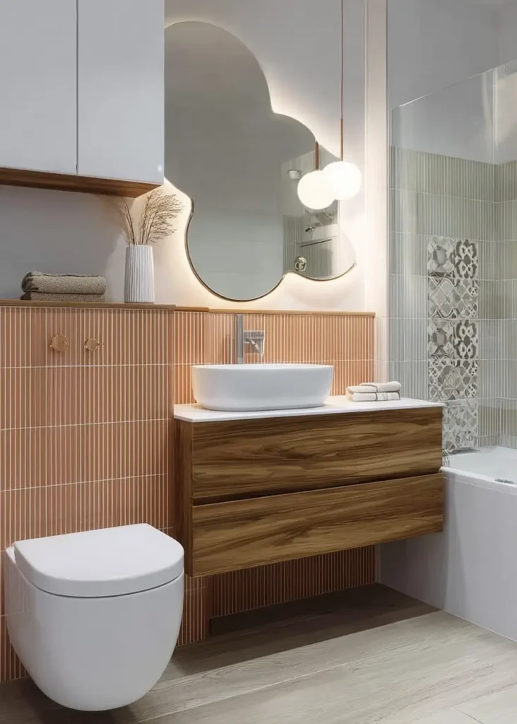 46 Scandinavian Bathroom Design Ideas for a Serene Sanctuary 33 Cloud-shaped backlit mirror above a walnut vanity with vertical pink tiles in a playful bathroom.