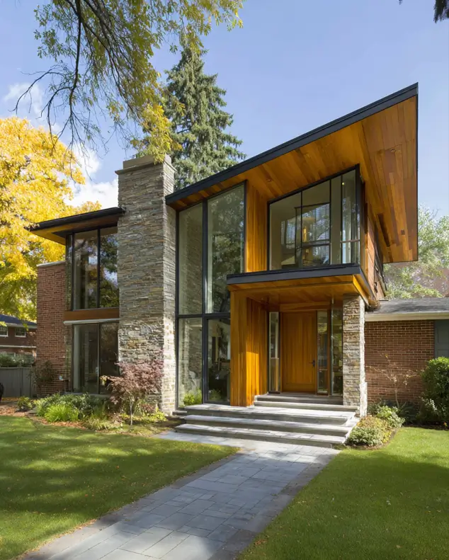 37 Mid Century Modern House Exteriors to Inspire Your Renovation 36 A multi-level mid century modern home exterior combining stone, brick, and natural wood, with a prominent glass entryway.