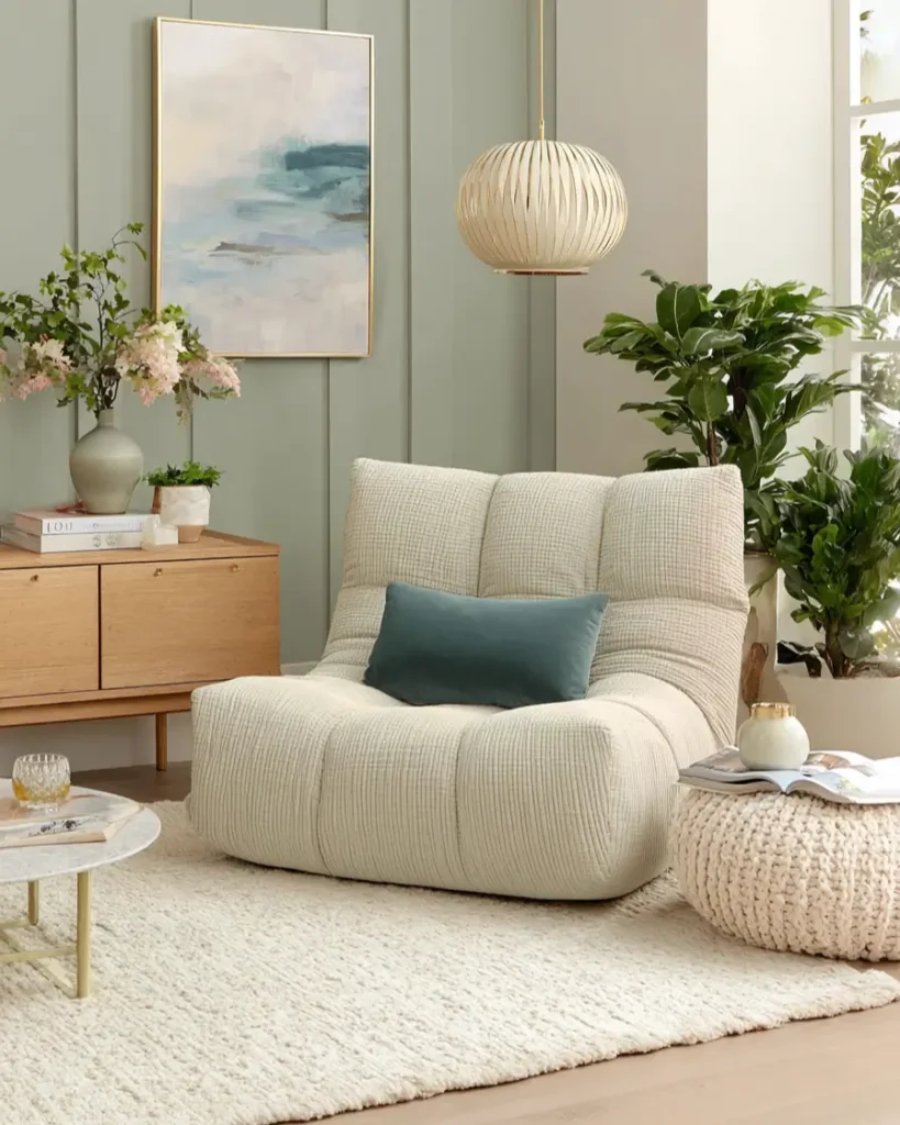Serene reading nook featuring soft sage green vertical paneling and a comfortable cream lounge chair.