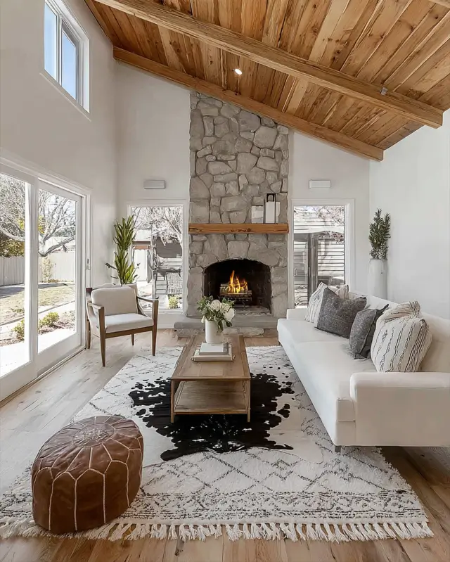 Modern ranch interior design living room with a tall stone fireplace and vaulted wood ceiling.