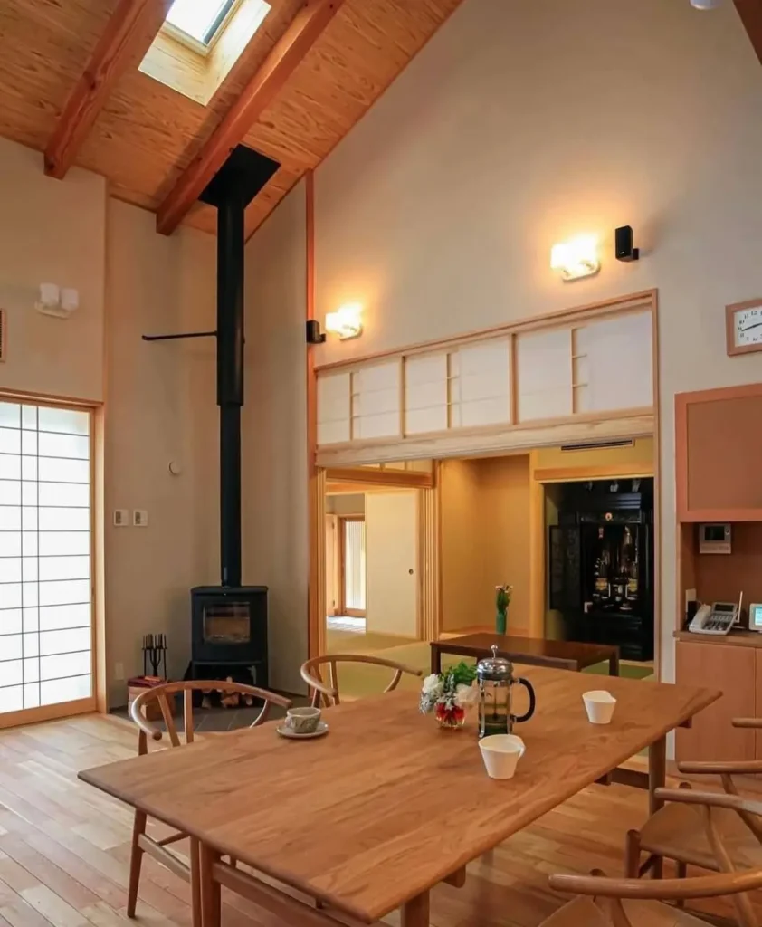 A modern Japanese dining room with a vaulted wood ceiling, shoji screens, and a wooden table.