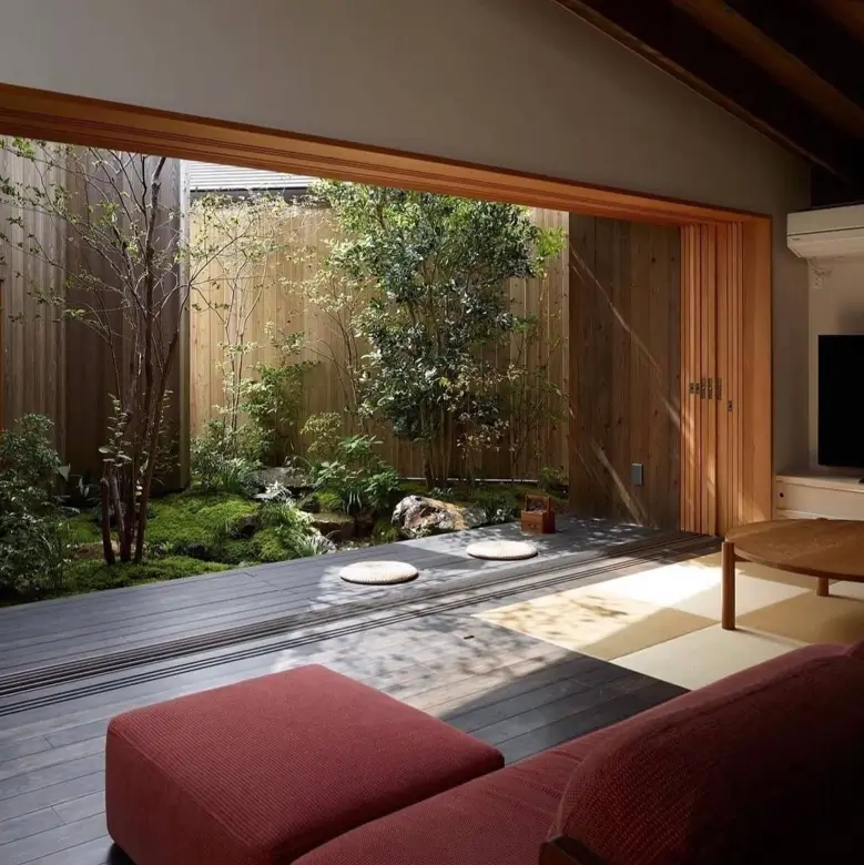 A Japanese house interior idea showing a room opening onto a dark wood veranda and a private green garden.
