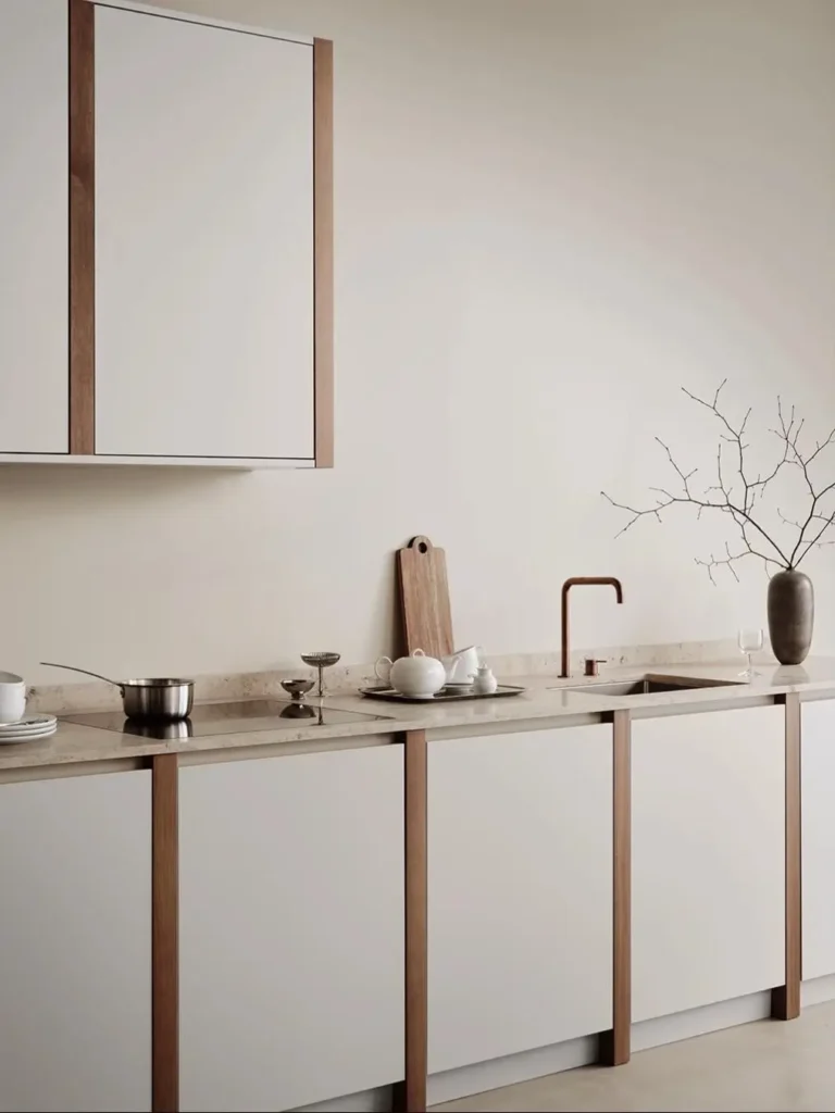 A minimal Japanese style kitchen with off-white cabinets framed in dark wood and a stone countertop.