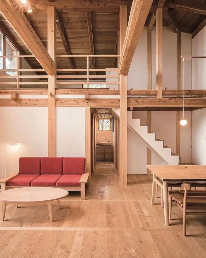 A modern Japan house interior design featuring exposed wooden beams, hardwood floors, and simple furniture.