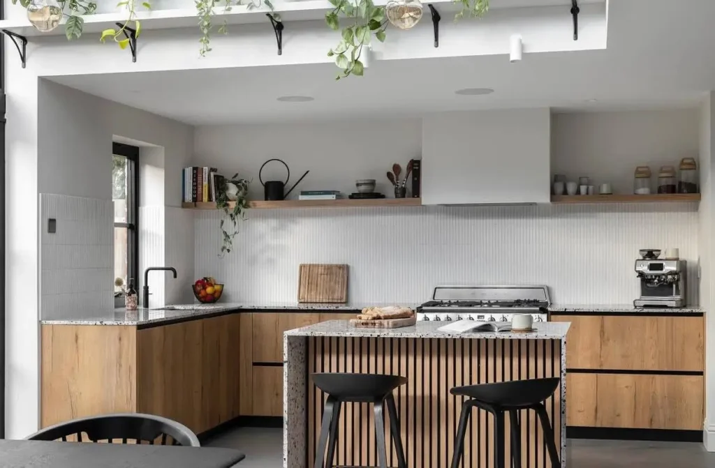 A Japanese inspired kitchen with a fluted wood island, reeded tile backsplash, and light wood cabinets.