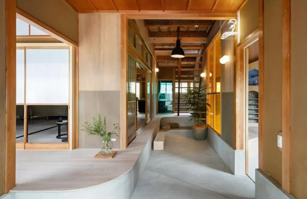 A modern Japanese hallway with concrete floors, wood framing, and a raised platform.