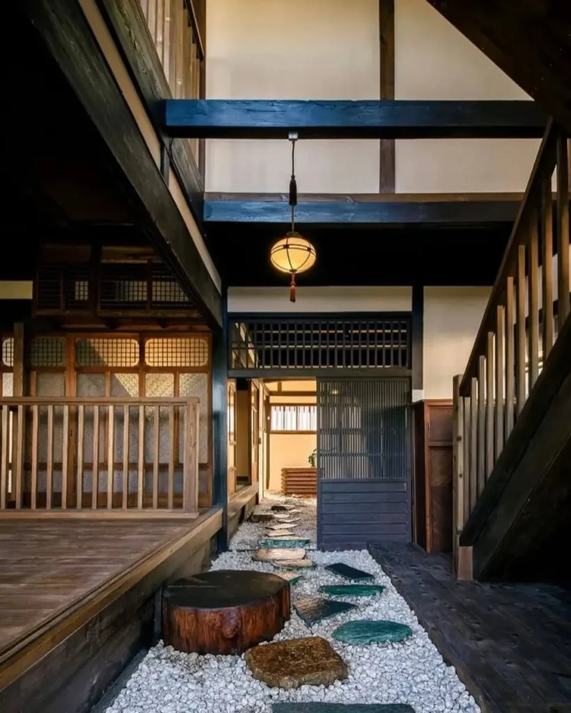 A traditional Japanese house interior with an indoor stepping stone path on gravel, surrounded by dark wood beams.