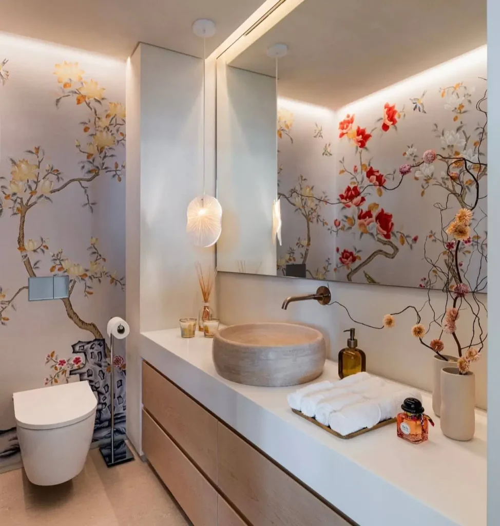 26 Japanese Bathroom Design Ideas for a Serene Home Oasis 11 A Japanese inspired bathroom in Dubai with a hand-painted floral garden wall, light wood vanity, and stone vessel sink.
