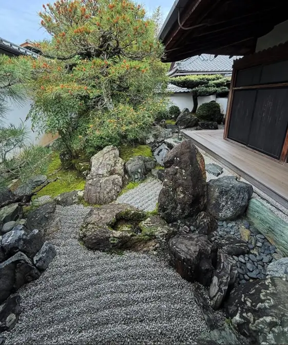 Natural zen garden path with large gravel and asymmetrical, moss-covered stones.