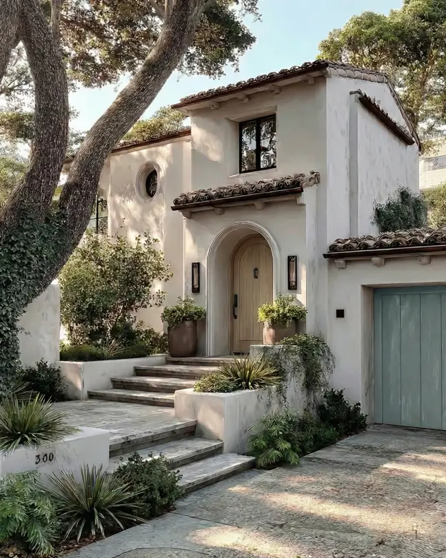 38 Small Mediterranean-Style Homes That Define Coastal Charm 11 Rustic contemporary small Mediterranean house design featuring muted plaster, tiered steps, and a natural wood arched door.