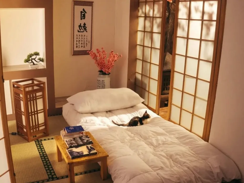 A serene traditional Japanese bedroom featuring a futon on tatami mats, shoji screens diffusing warm light, and a low wooden table.