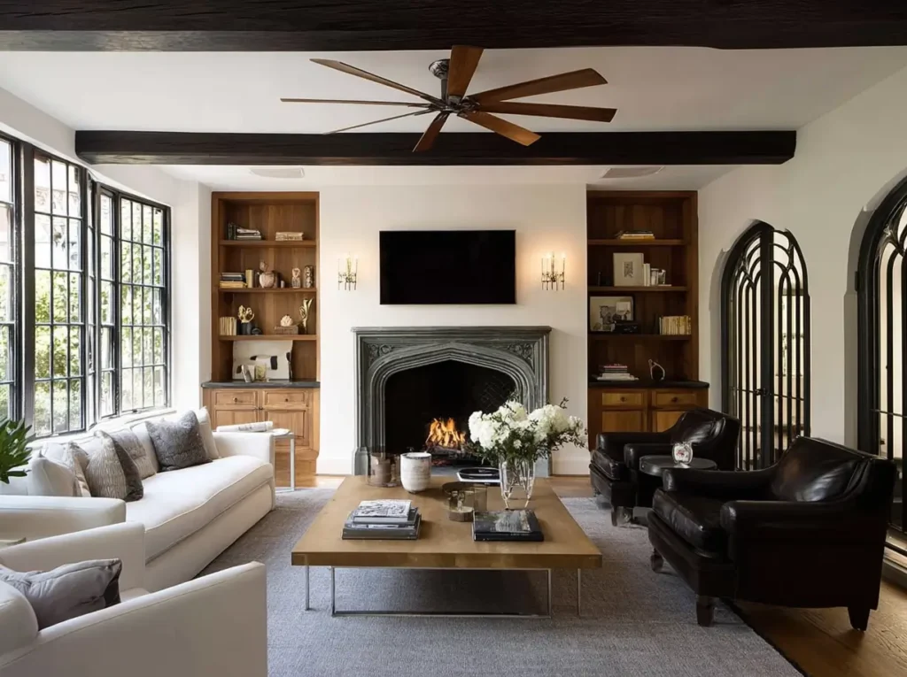 A modern Tudor interior design living room with white walls, dark ceiling beams, and a carved stone fireplace.