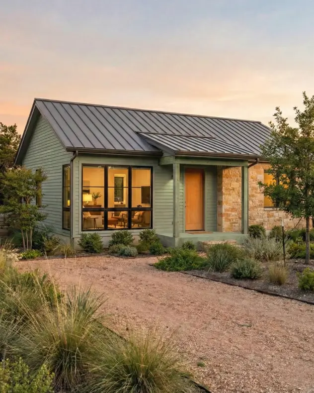 26 Small Ranch-Style House Ideas for Timeless Modern Living 15 Sage green siding and limestone accents on a small Ranch house design featuring corner windows with warm lighting.
