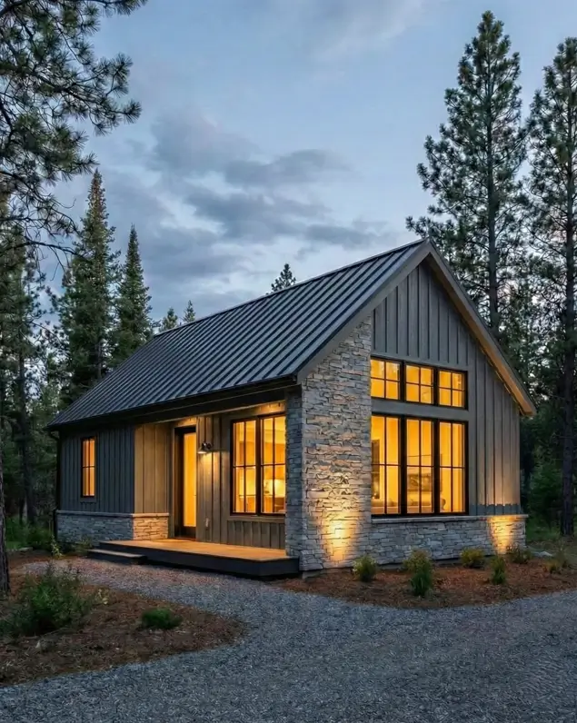 33 Small Scandinavian House Ideas That Prove Less Is More 17 Modern stone cabin featuring grey siding, rugged stone accents, and large windows at dusk.