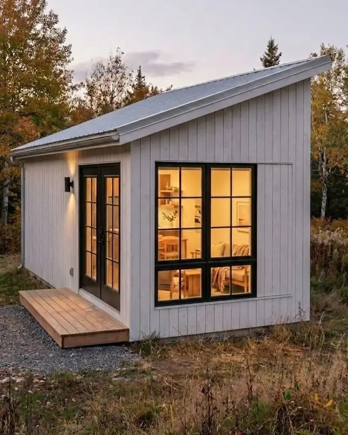 33 Small Scandinavian House Ideas That Prove Less Is More 18 Compact mono-pitch studio with white cladding and black-framed glazing, ideal as a backyard ADU.