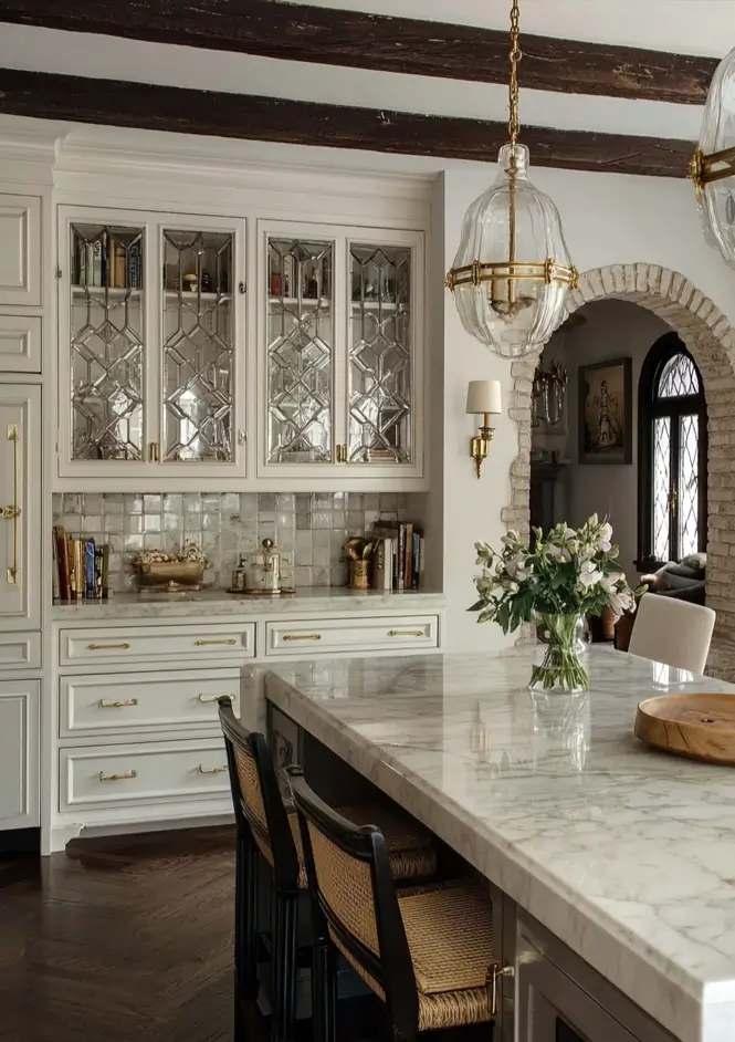 34 Modern Tudor Kitchen Ideas: Old-World Charm, New Appeal 35 Kitchen featuring white cabinets with diamond leaded glass, a marble island, and a stone archway.