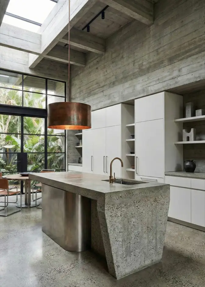 38 Modern Brutalist Interior Design Ideas for a Raw, Livable Sanctuary 6 Modern concrete interiors in a kitchen featuring a tapered island and oversized copper pendant light.