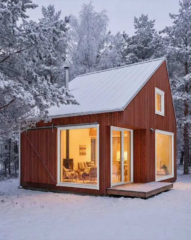 33 Small Scandinavian House Ideas That Prove Less Is More 11 Small Scandinavian house with a glass front, red exterior, and sliding barn door shutter in winter.