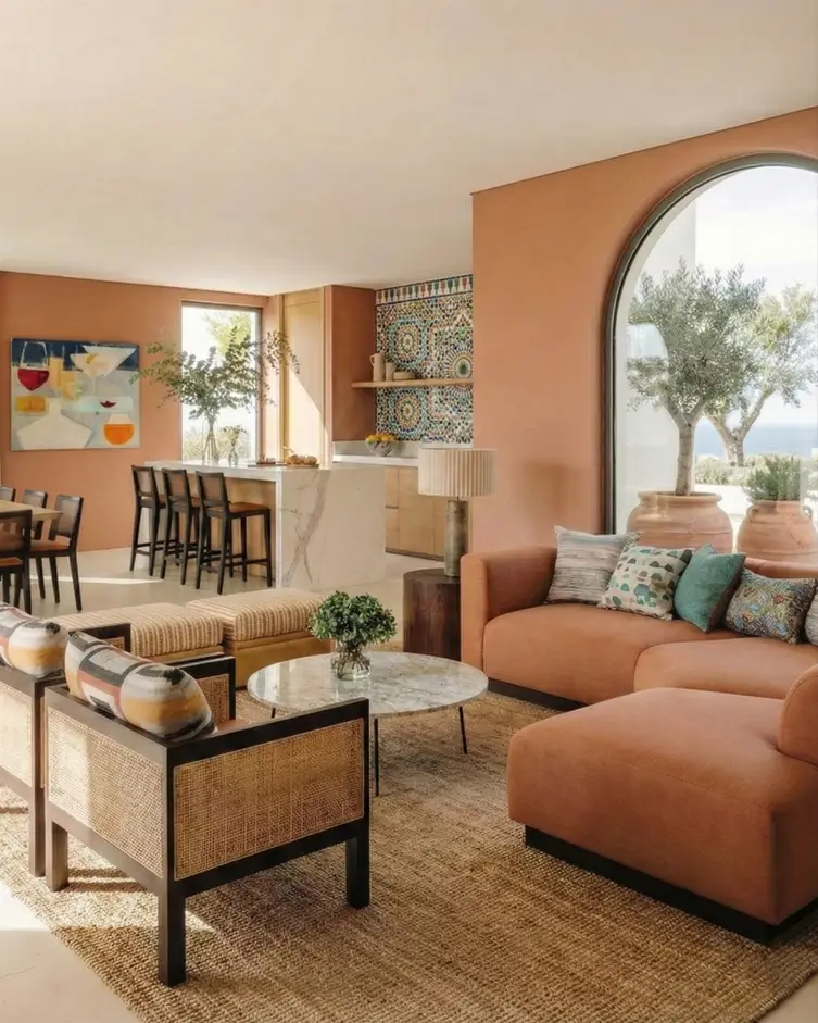 27 Modern Mediterranean Interior Design Ideas That Feel Effortlessly Chic 16 Expansive living area enveloped in warm terracotta hues with a massive arched window and contrasting patterned kitchen tiles.