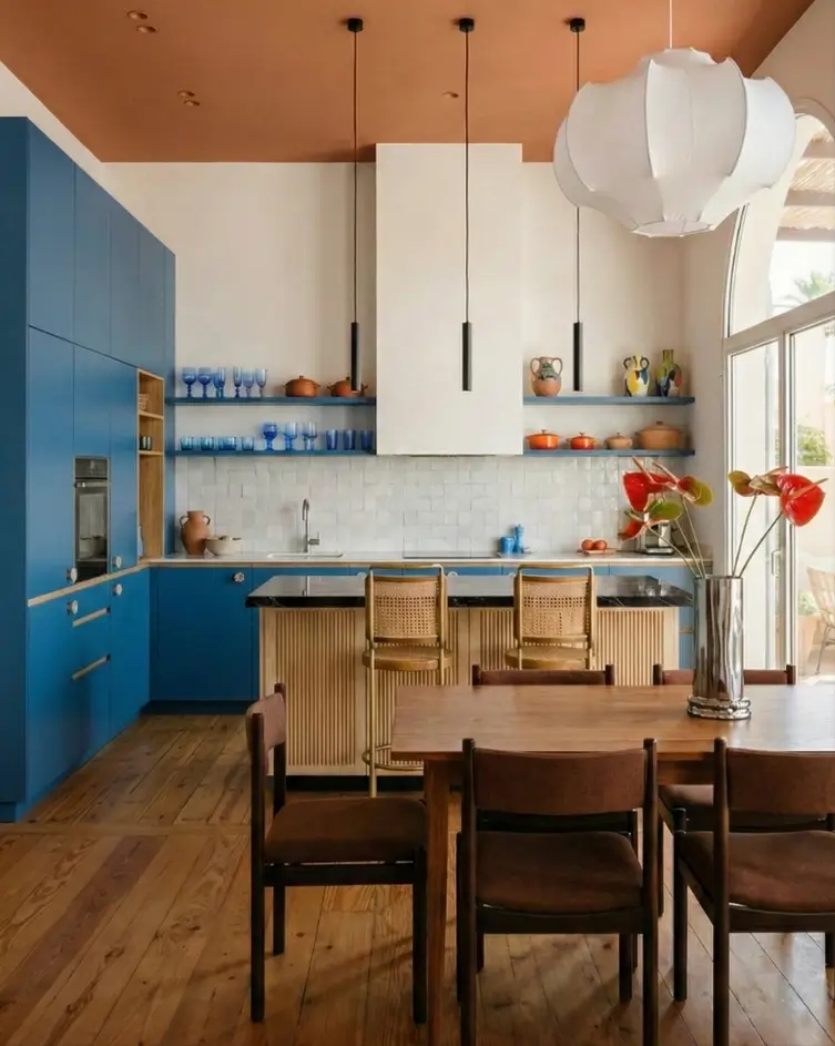 30 Mediterranean Kitchen Ideas for a Warm, Coastal Escape 7 Modern Mediterranean kitchen design featuring blue cabinets, terracotta ceiling, fluted wood island, and paper pendant light.