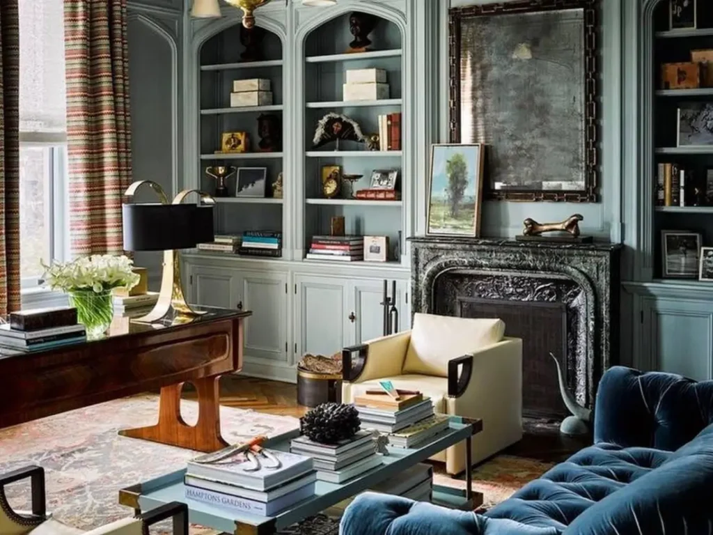 25 Modern Victorian Living Room Ideas That Feel Timeless and Fresh 54 Modern Victorian living room featuring teal blue built-in shelves with Gothic arches, a dark marble fireplace, and a blue tufted velvet sofa in a curated, multi-purpose space.