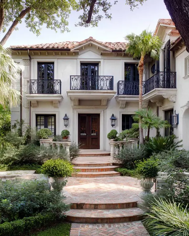 45 Colonial House Design Ideas for a Timeless Exterior 13 Spanish Colonial home with white stucco walls, terracotta tile roof, iron Juliet balconies, and herringbone brick steps