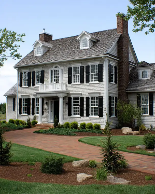 45 Colonial House Design Ideas for a Timeless Exterior 24 Cape Cod shingled Colonial home with cedar shake siding, black shutters, brick chimney, and curved paver driveway