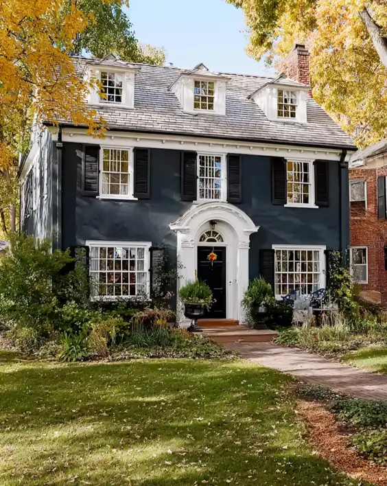 45 Colonial House Design Ideas for a Timeless Exterior 27 Dark charcoal painted Colonial home with white trim, broken pediment entry, black shutters, and three small dormers in autumn