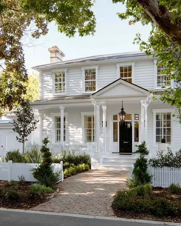 45 Colonial House Design Ideas for a Timeless Exterior 5 White Colonial home with covered front porch, slim columns, hanging lantern, and brick walkway