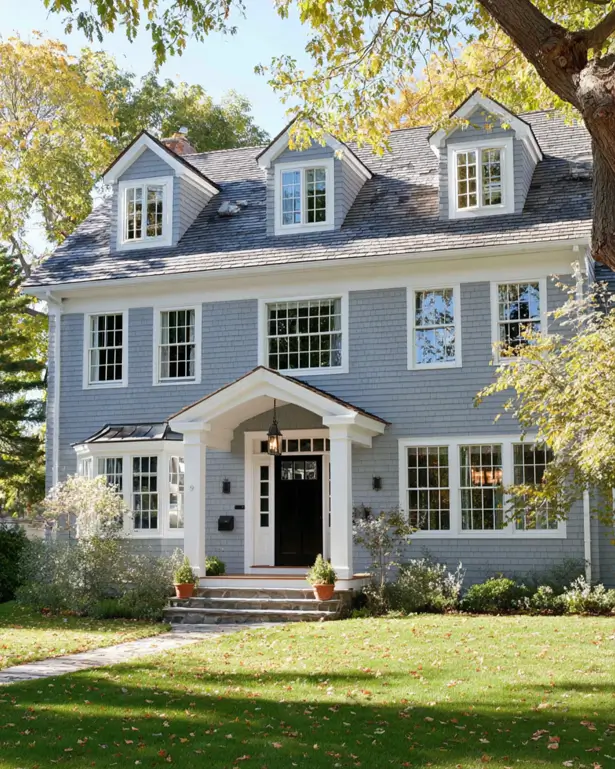 45 Colonial House Design Ideas for a Timeless Exterior 34 Light blue-gray painted shingle Colonial home with three gabled dormers, white trim, small bay window, and pedimented entry hood