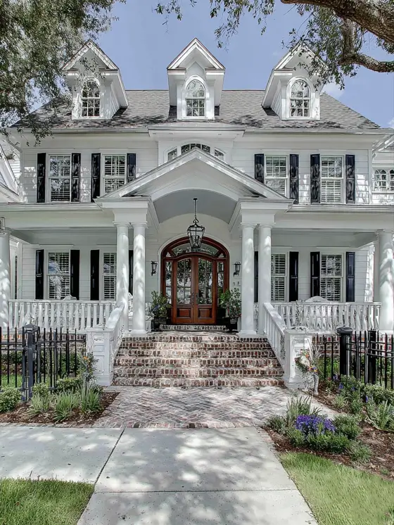 45 Colonial House Design Ideas for a Timeless Exterior 44 Grand white Colonial home with arched roof portico, double wood front doors, arched transom, three peaked dormers, and herringbone brick steps