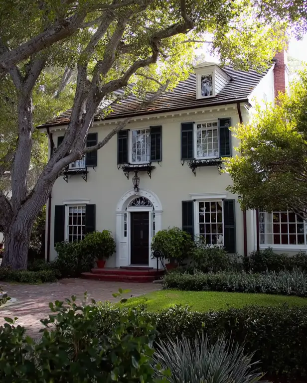 45 Colonial House Design Ideas for a Timeless Exterior 10 Cream stucco Colonial home with dark shutters, arched fanlight transom, dentil molding, and mature shade trees
