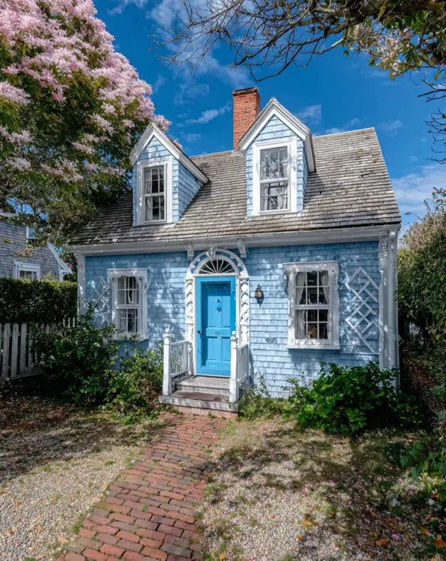 27 Cape Cod Style House Ideas for a Timeless New England Exterior 18 Powder-blue clapboard cottage with matching front door, carved fan transom, lattice window screens, twin dormers, and brick walkway