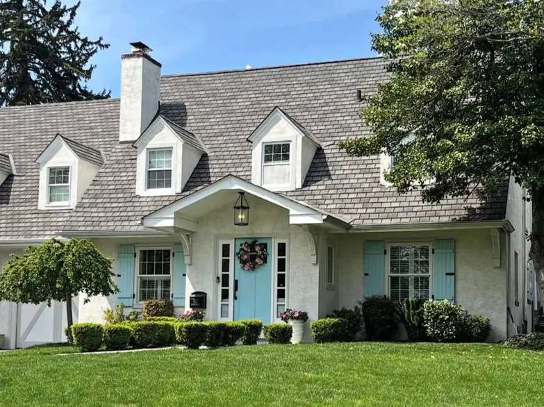 27 Cape Cod Style House Ideas for a Timeless New England Exterior 6 Cream stucco home with mint board-and-batten shutters, matching front door, three dormers, and bracketed entry hood