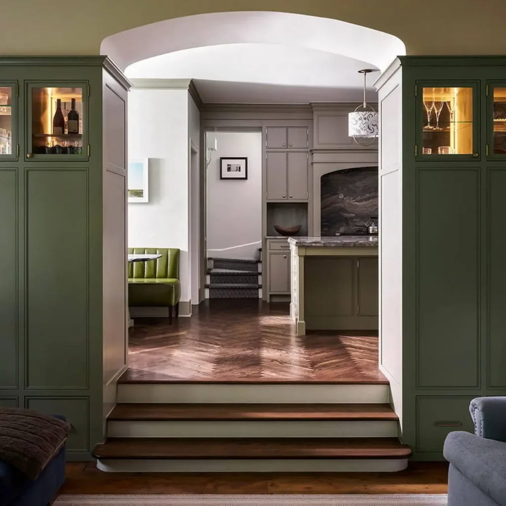 Colonial Interior Design Style: American vs. British (33 Real-Home Ideas) 24 American Colonial interior with barrel-arched opening, green built-in cabinetry, herringbone wood floors, and glass-front cabinets