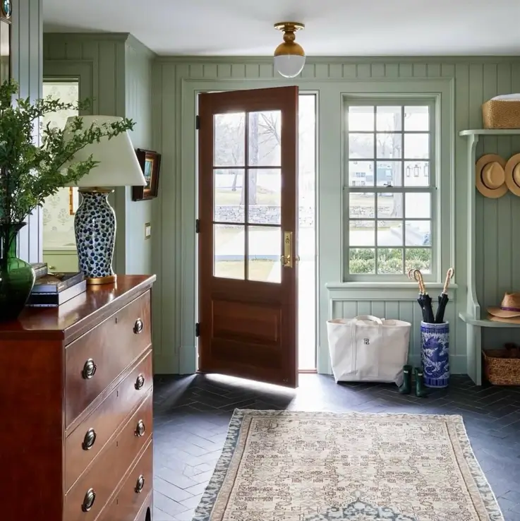 Colonial Interior Design Style: American vs. British (33 Real-Home Ideas) 5 American Colonial entryway with sage green paneling, antique mahogany chest, and herringbone tile floor