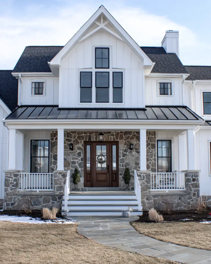 White Farmhouse with Stone Exterior: 29 Ideas That Feel Warm, Not Cold 15 Gray fieldstone porch walls framing a walnut front door on a white farmhouse