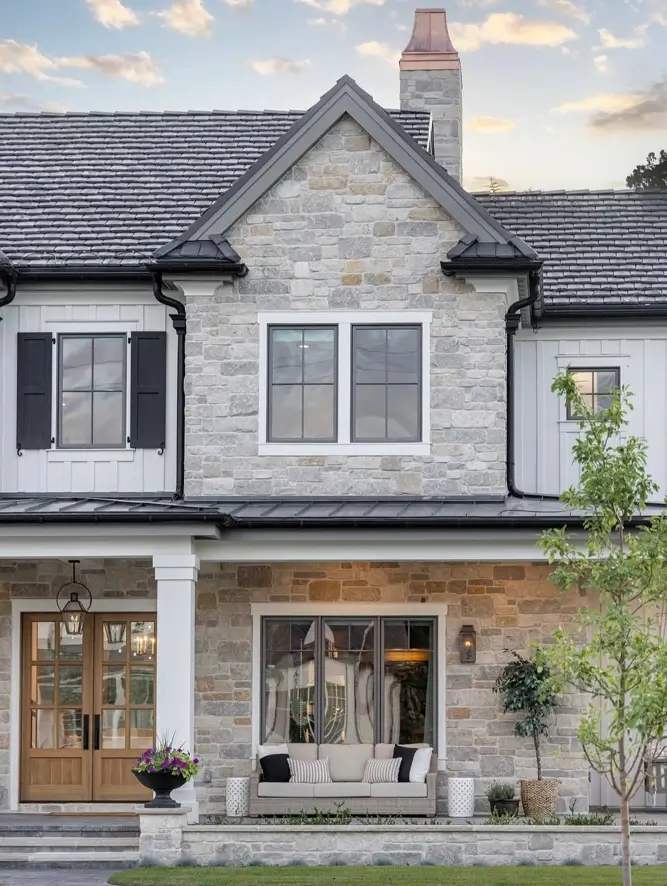 White Farmhouse with Stone Exterior: 29 Ideas That Feel Warm, Not Cold 18 Buff stone center bay rising from a covered farmhouse porch with board and batten siding